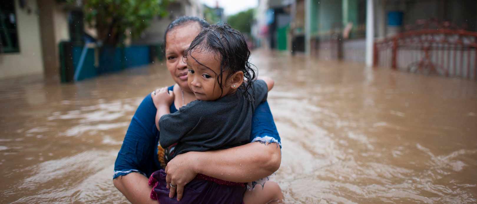 Woman carrying child through flooded streat
